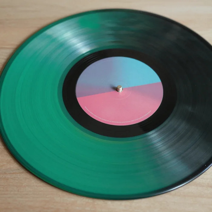 A close-up of a colored vinyl record catching neon light