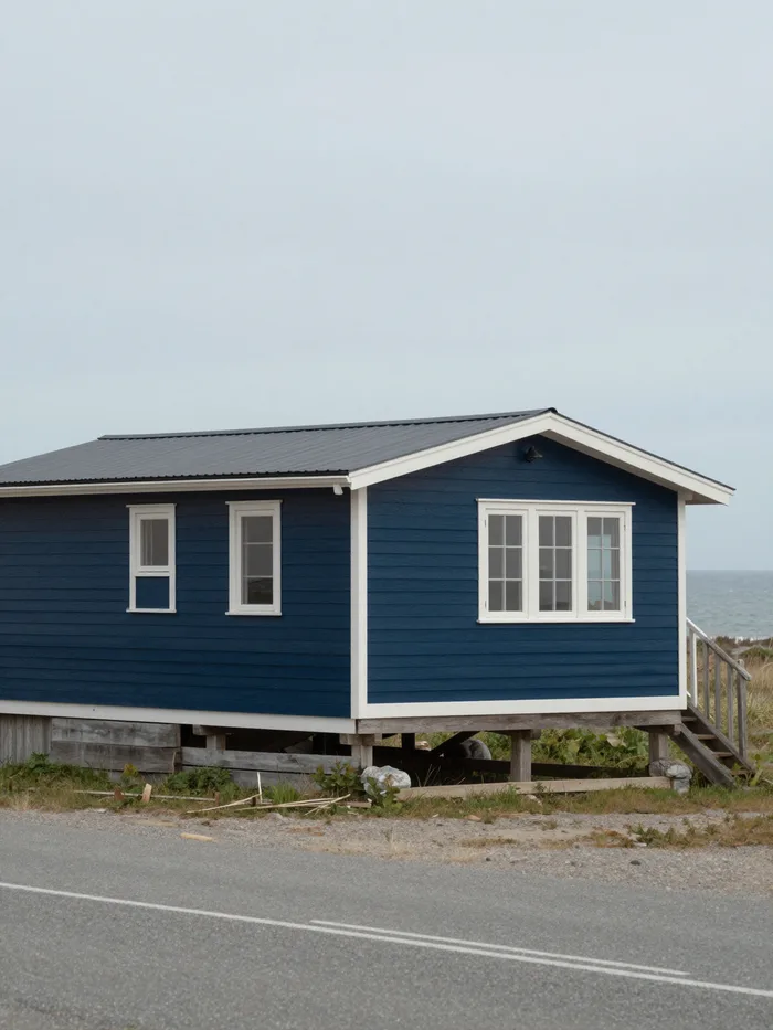 A low-slung timber coastal house against a grey sky, calm architecture