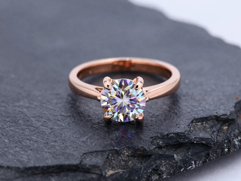 A diamond band in rose gold catching prismatic light on dark stone, elegant macro